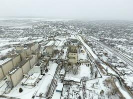 Sprinkled with snow grain elevator. Winter view of the old Soviet elevator. Winter view from the bird's eye view of the village. The streets are covered with snow photo