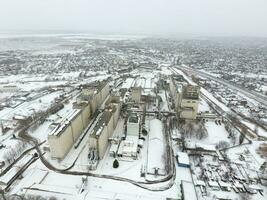 Sprinkled with snow grain elevator. Winter view of the old Soviet elevator. Winter view from the bird's eye view of the village. The streets are covered with snow photo