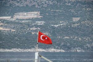 el bandera de Turquía revolotea en el viento en el cubierta de Placer yate. foto