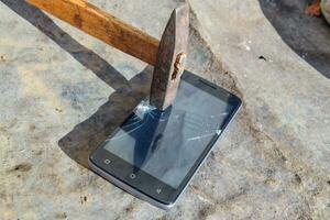 Hammer and smartphone. The screen of the smartphone, a broken ha photo