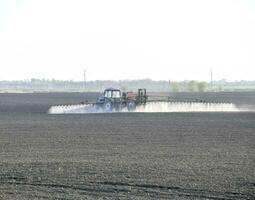 The tractor sprayed herbicides on the field. Chemistry in agricu photo