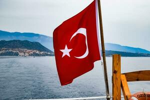The flag of Turkey flutters in the wind on the deck of pleasure yacht. photo