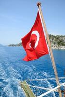 Turkey flag at the stern of a pleasure yacht. View of Mediterranean coast photo