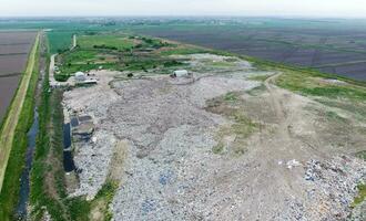 garbage dump with heaps of garbage and treatment facilities. Landfill of garbage outside the village photo