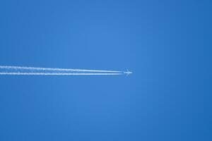 Condensation trail from an airplane in a blue sky photo