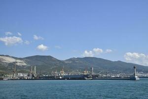 carga Puerto con Puerto grúas mar bahía y montañoso costa. foto