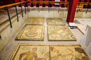 Ancient antique mosaic. Image of hunting scenes and animals. Portraits of people. photo