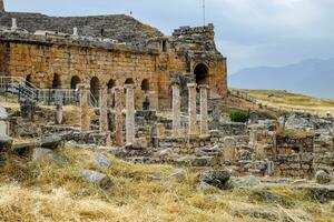 Ancient antique amphitheater in city of Hierapolis in Turkey. Side view. Steps and antique statues with columns in the amphitheater photo