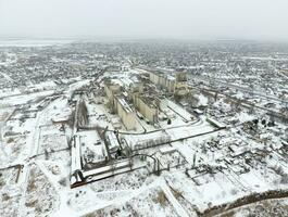 Sprinkled with snow grain elevator. Winter view of the old Soviet elevator. Winter view from the bird's eye view of the village. The streets are covered with snow photo