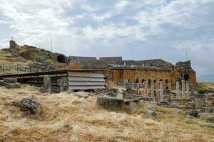 Ancient antique amphitheater in city of Hierapolis in Turkey. Side view. Steps and antique statues with columns in the amphitheater photo