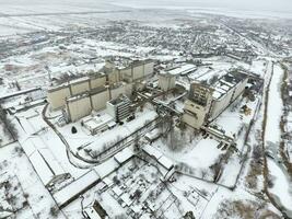 Sprinkled with snow grain elevator. Winter view of the old Soviet elevator. Winter view from the bird's eye view of the village. The streets are covered with snow photo