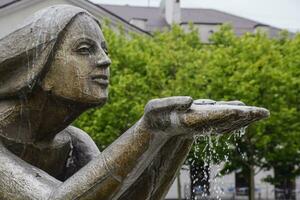 Statue of kneeling woman in the fountain. Water flowing from the hands of the statue photo