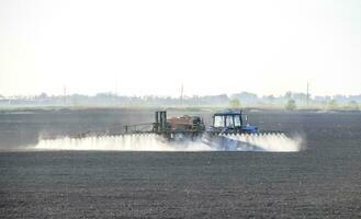 el tractor rociado herbicidas en el campo. química en agricu foto