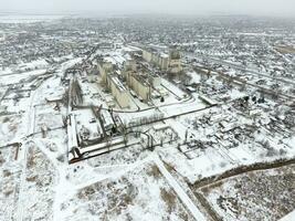 Sprinkled with snow grain elevator. Winter view of the old Soviet elevator. Winter view from the bird's eye view of the village. The streets are covered with snow photo