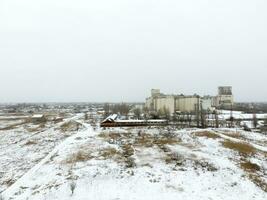 Sprinkled with snow grain elevator. Winter view of the old Soviet elevator. Winter view from the bird's eye view of the village. The streets are covered with snow photo