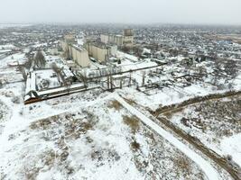 Sprinkled with snow grain elevator. Winter view of the old Soviet elevator. Winter view from the bird's eye view of the village. The streets are covered with snow photo