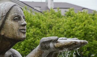 Statue of kneeling woman in the fountain. Water flowing from the hands of the statue photo