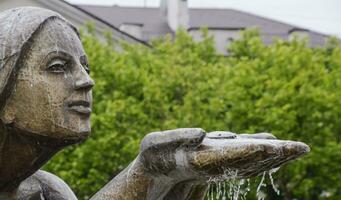 estatua de arrodillado mujer en el fuente. agua fluido desde el manos de el estatua foto