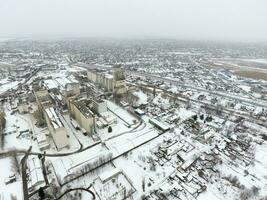 Sprinkled with snow grain elevator. Winter view of the old Soviet elevator. Winter view from the bird's eye view of the village. The streets are covered with snow photo