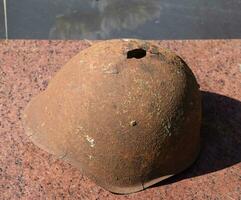 el antiguo de soldado protector casco. el casco con un agujero. el acero casco en el Monumento foto