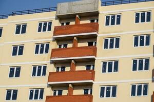 wall of a high-rise brick house, red balconies and yellow walls. photo