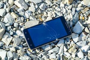 Frustrated phone on the rocks. Glass shattered on rocks on a sma photo
