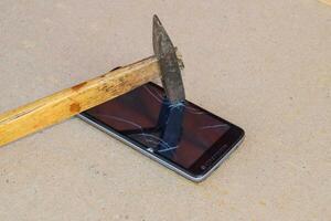 Hammer and smartphone. The screen of the smartphone, a broken ha photo