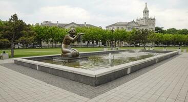 Statue of kneeling woman in the fountain. Water flowing from the hands of the statue photo