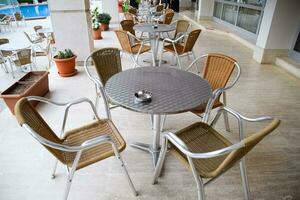 metal mesas y sillas con mimbre asientos en al aire libre cafetería. foto