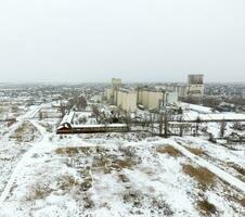 Sprinkled with snow grain elevator. Winter view of the old Soviet elevator. Winter view from the bird's eye view of the village. The streets are covered with snow photo