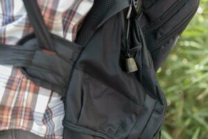 A person who wear a backpack with bear bell at the green forest in Autumn photo