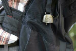 A backpack with bear bell at the green forest in Autumn closeup photo