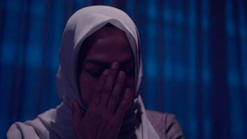 Woman wearing a hijab is crying sitting on a bed. video