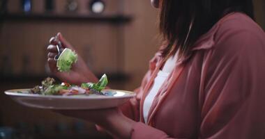 cenas fechar acima do jovem ásia mulher comendo vegetal salada dentro cozinha às casa, saudável Comida e bem estar conceito video