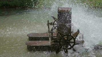 Old rusty floating water turbine rotating wheel paddles for increasing oxygen quality in water source. Splashing water. Slow motion. video