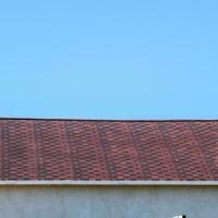 Roof from multi-colored bituminous shingles. Patterned bitumen shingles. Bituminous burgundy roof. photo