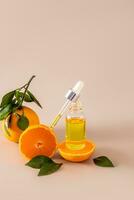 An open bottle with a cosmetic product for face and body skin care and a pipette filled with it against of fresh tangerines. moisturizing serum. photo