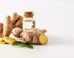 Glass bottle with cork cap with natural ginger root oil stands on a large fresh plant root on a white background. Front view. packaging. photo