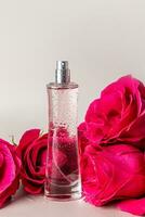 A chic tall bottle of women's perfume on a pastel background with a three tea rose. Vertical view. Presentation of the delicate fragrance of perfume. photo