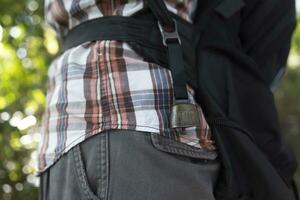 A person who wear a backpack with bear bell at the green forest in Autumn photo