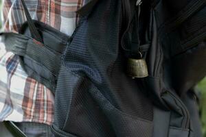 A person who wear a backpack with bear bell at the green forest in Autumn photo