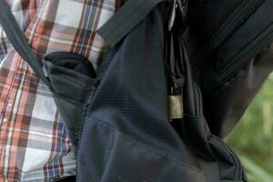 A person who wear a backpack with bear bell at the green forest in Autumn photo