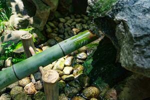A Japanese Bamboo Water Fountain Shishi-Odoshi in Zen Garden photo