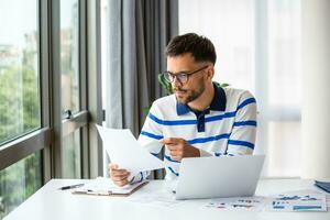 Business professionals. Business man analyzing data using computer while spending time in the office. Young grinning professional man in office. Graphs and charts photo