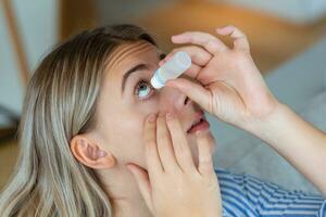 Woman using eye drop, woman dropping eye lubricant to treat dry eye or allergy, sick woman treating eyeball irritation or inflammation woman suffering from irritated eye, optical symptoms photo