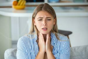 Close up of young woman rubbing her inflamed tonsils, tonsilitis problem, cropped. Woman with thyroid gland problem, touching her neck, girl has a sore throat photo