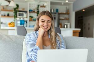 bonito hermosa dama trabajo a el cuaderno sentar abajo en el sofá a hogar - cheque en oline tiendas para ciber lunes ventas - tecnología mujer concepto para alternativa oficina Lanza libre foto