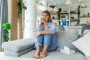 Unhappy young woman covering face with hands, crying alone close up, depressed girl sitting on couch at home, health problem or thinking about bad relationships, break up with boyfriend, divorce photo