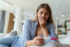 Shocked woman looking at control line on pregnancy test. Single sad woman complaining holding a pregnancy test . Depressed woman holding negative pregnancy test. photo