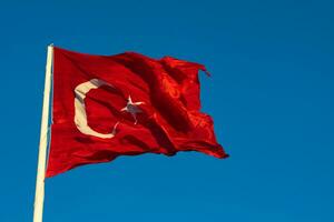 Waving Turkish Flag at sunset isolated on blue sky background photo